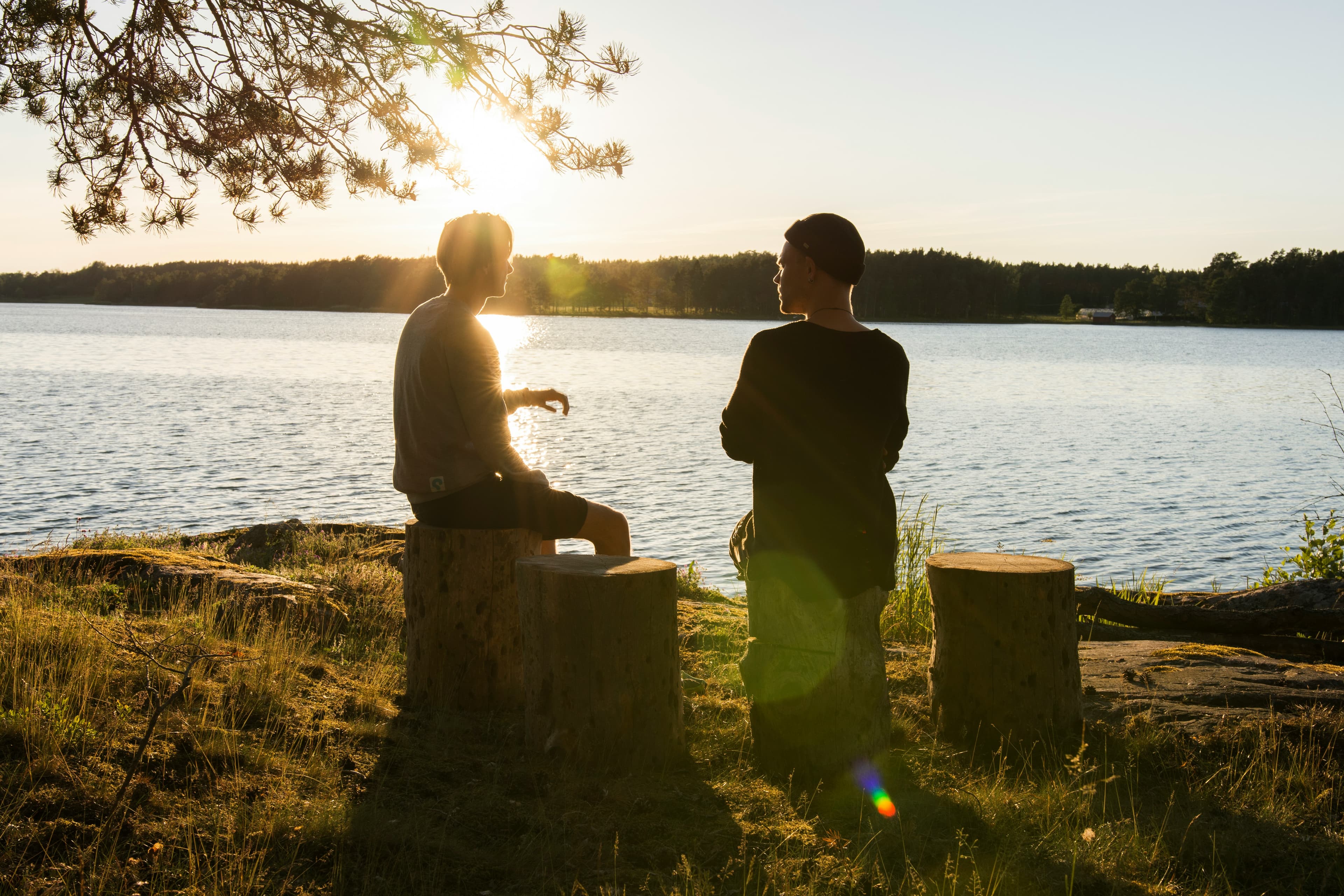 To unge mennesker i samtale ved en sø i solnedgang